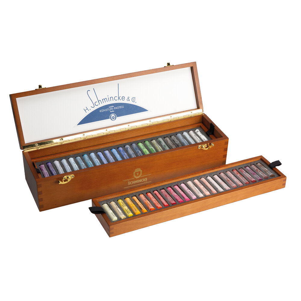 Hoekopname van de geopende Schmincke retro kist. De bovenste houten inlay met pastels is uit de kist getild, waardoor de onders