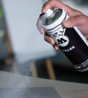 Actiefoto van een hand die de Molotow Urban Fine-Art Filler spuitbus aanbrengt op een oppervlak.