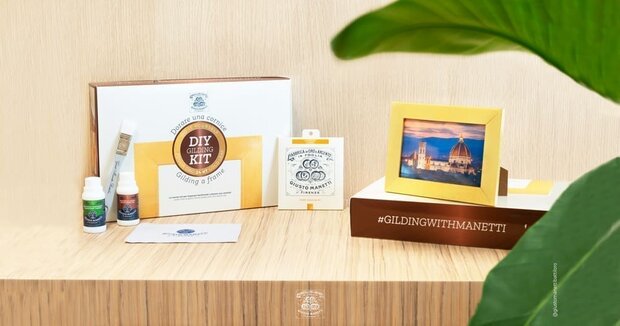 Een sfeervolle lifestyle foto van de voltooide Manetti DIY Gilding Kit. Bovenop de bruin met witte productdoos en wat witte boe